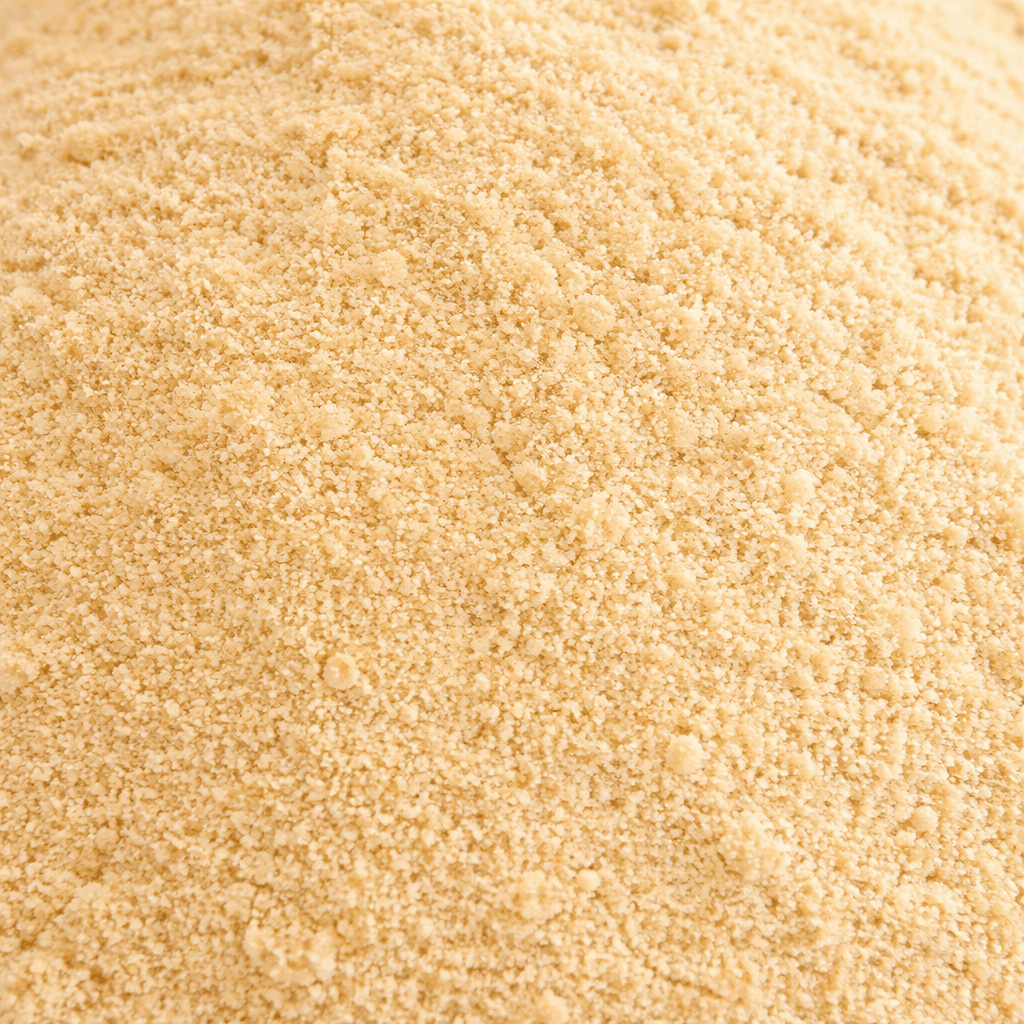Close-up of light brown granulated sugar with a fine, sandy texture and small clumps.