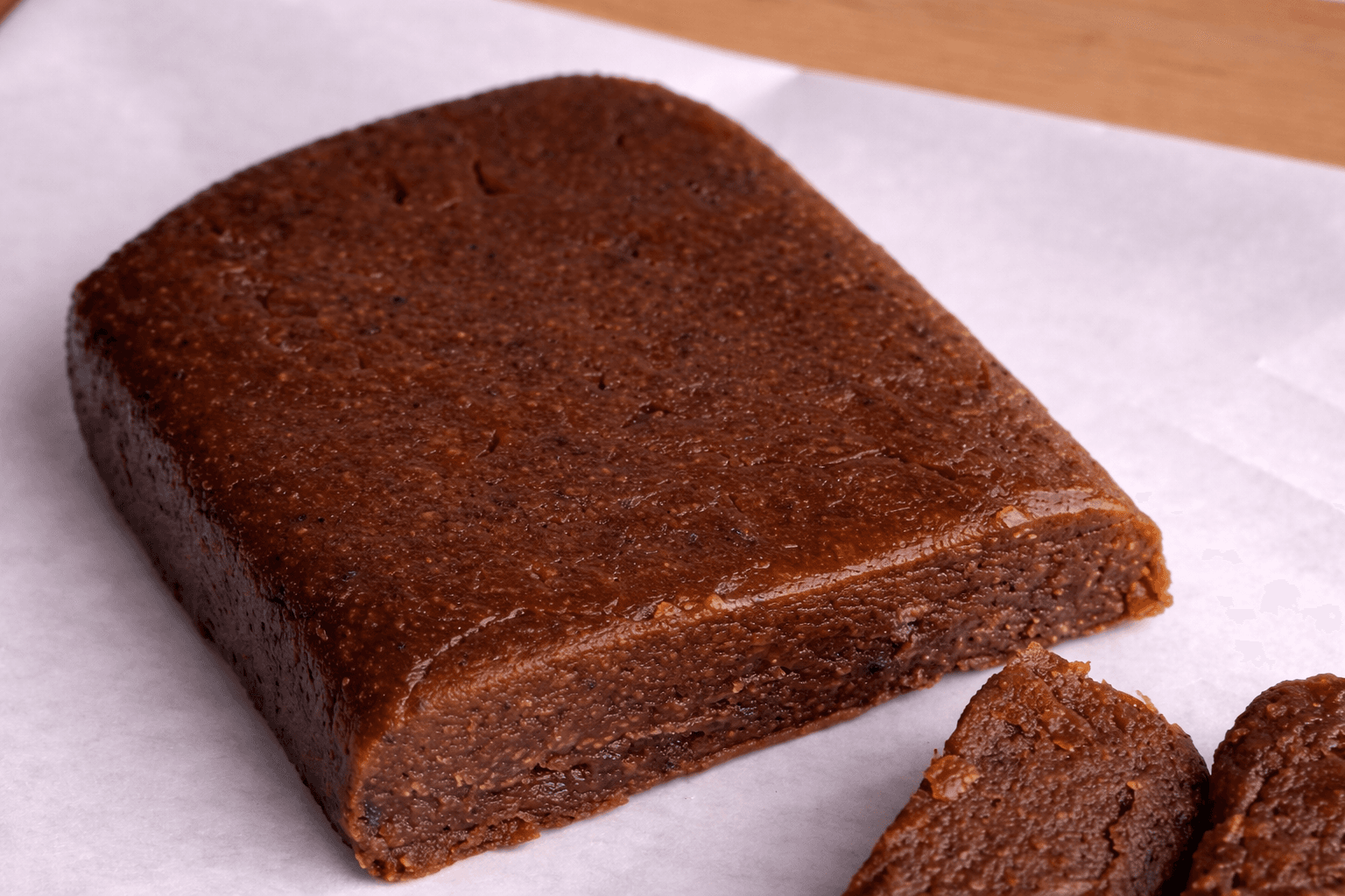 Dense, dark brown rectangular block of fruit paste resting on white parchment paper.