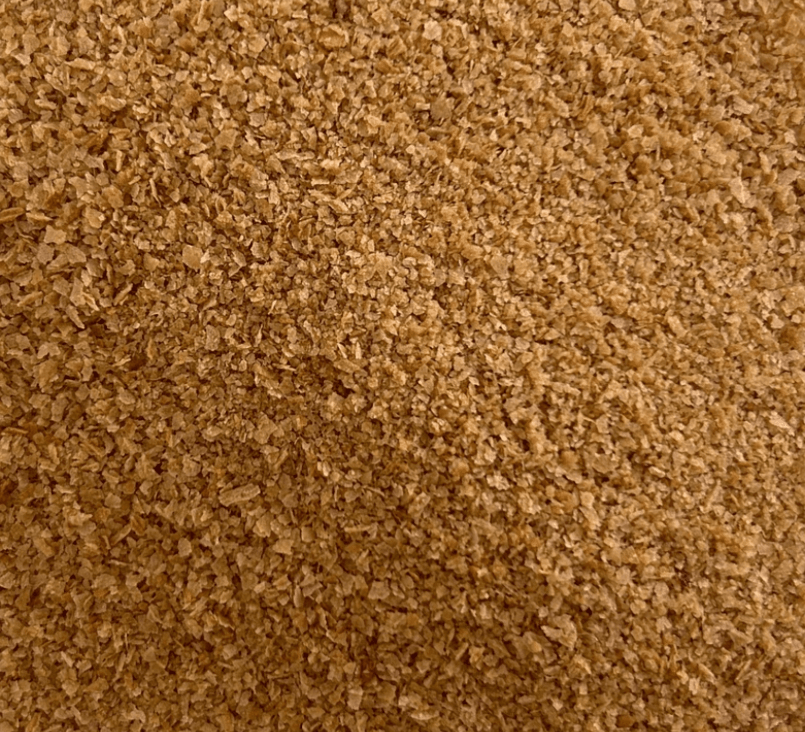 Close-up of small, light brown, flaky granules of wheat germ or bran spread evenly.